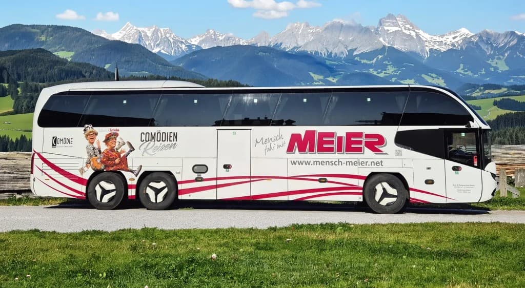 Comödien-Reisen Bus vor Alpenkulisse — unterwegs mit der Comödie Fürth